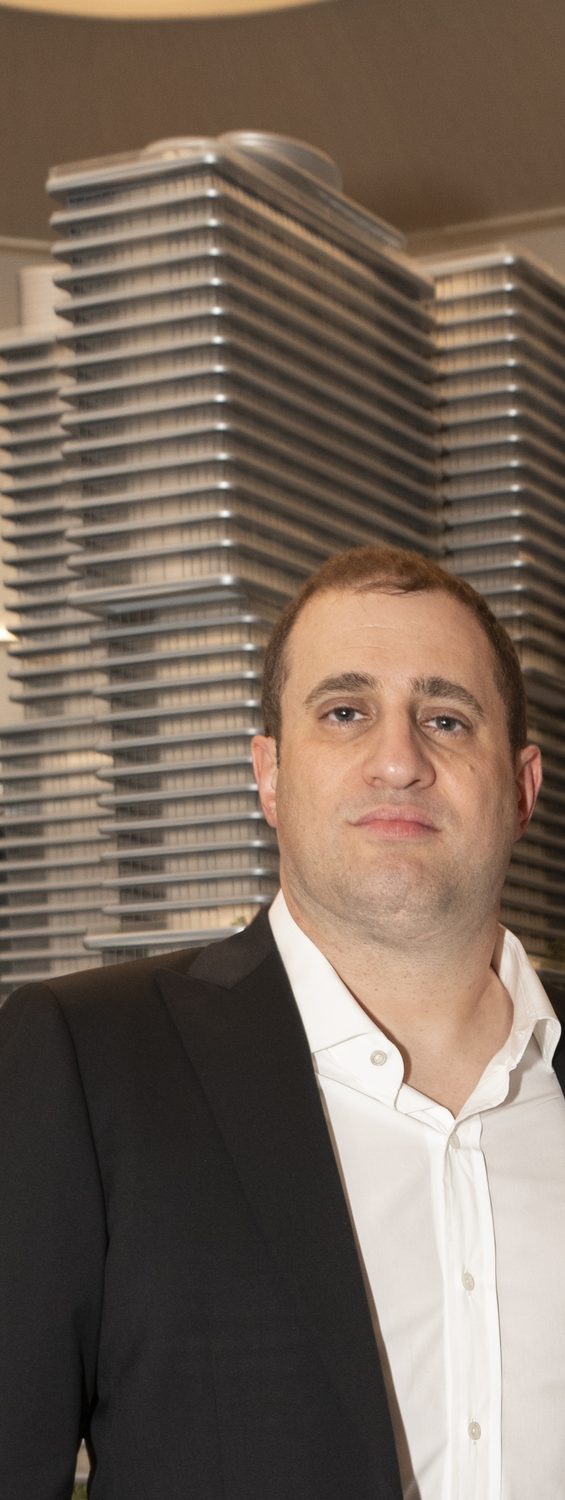 Michael Stern stands in front of an architectural scale model of a stepped tower.